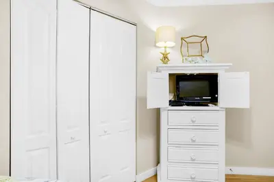 a white bedroom with a tv and a white dresser at Aquavista 304W in Panama City Beach