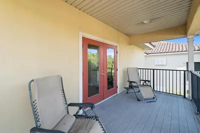 a porch with two chairs and a red door at La Valencia Villas in Rosemary Beach