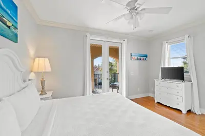a white bedroom with a bed and a tv at La Valencia Villas in Rosemary Beach
