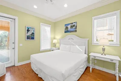 a bedroom with a white bed and two windows at La Valencia Villas in Rosemary Beach