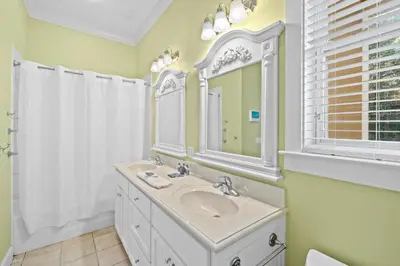 a white bathroom with a sink and a mirror at La Valencia Villas in Rosemary Beach
