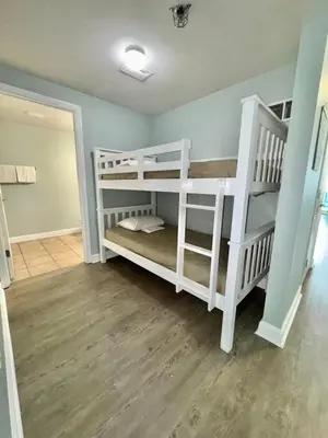 two white bunk beds in a room with wooden floors at Shores of Panama Resort in Panama City Beach