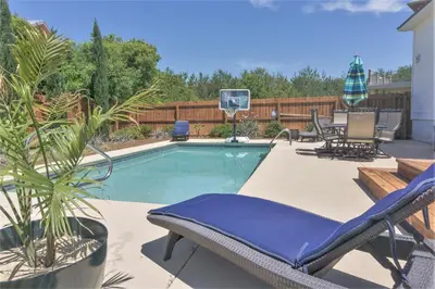 a patio with a pool with chairs and a basketball hoop at 30A Beach House - Walking on Sunshine in Inlet Beach