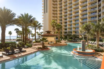 a pool at the resort with palm trees and a building at Shores of Panama by Panhandle Getaways in Panama City Beach