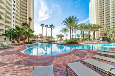 a pool at the resort with chairs and palm trees at Shores of Panama by Panhandle Getaways in Panama City Beach