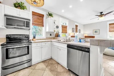 a kitchen with white cabinets and stainless steel appliances at Blue Sky Bungalow 156 in Seagrove Beach