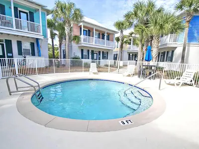a swimming pool in a courtyard with palm trees at Blue Sky Bungalow 156 in Seagrove Beach