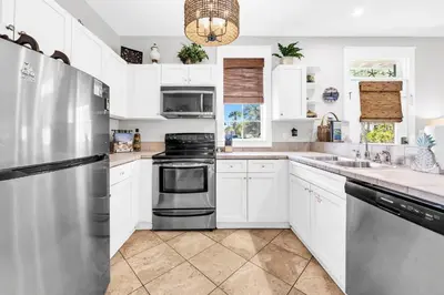 a kitchen with white cabinets and a stainless steel refrigerator at Blue Sky Bungalow 156 in Seagrove Beach