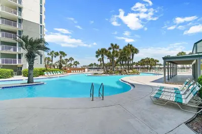 a swimming pool at a resort with chairs and palm trees at Long Beach Resort by Panhandle Getaways in Panama City Beach
