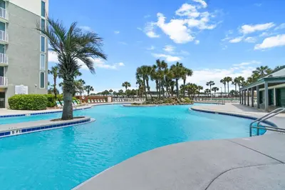 a swimming pool with palm trees and a building at Long Beach Resort by Panhandle Getaways in Panama City Beach