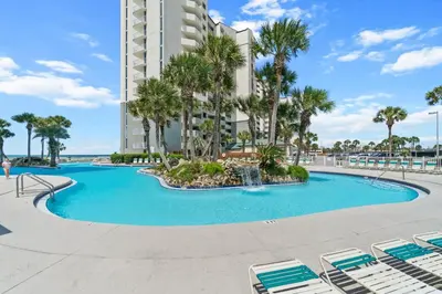 a swimming pool with palm trees and a building at Long Beach Resort by Panhandle Getaways in Panama City Beach