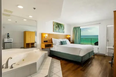 a hotel room with a bed and a bath tub at Beachcomber Beachfront Hotel, a By The Sea Resort in Panama City Beach