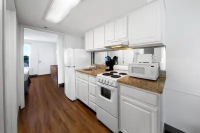 a kitchen with white cabinets and a white appliances at Beachcomber Beachfront Hotel, a By The Sea Resort in Panama City Beach