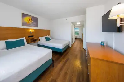 a hotel room with two beds and a tv at Beachcomber Beachfront Hotel, a By The Sea Resort in Panama City Beach