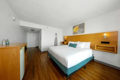 a bedroom with a large white bed and wooden floors at Beachcomber Beachfront Hotel, a By The Sea Resort in Panama City Beach