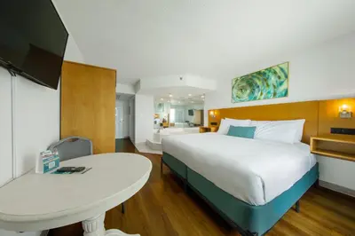 a bedroom with a large white bed and a table at Beachcomber Beachfront Hotel, a By The Sea Resort in Panama City Beach