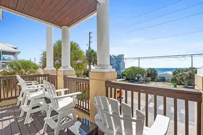 a porch with white chairs and a view of the ocean at Glory Daze Beach House by Panhandle Gateways in Sunnyside