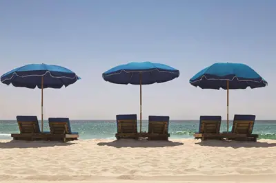 a group of chairs and umbrellas on a beach at Radisson Beachfront Hotel - Panama City Beach in Panama City Beach