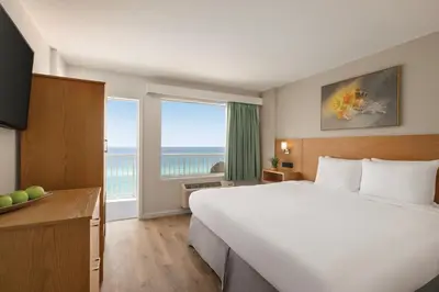 a hotel room with a large bed and a large window at Radisson Beachfront Hotel - Panama City Beach in Panama City Beach