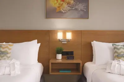 a hotel room with two beds and a table with a clock at Radisson Beachfront Hotel - Panama City Beach in Panama City Beach