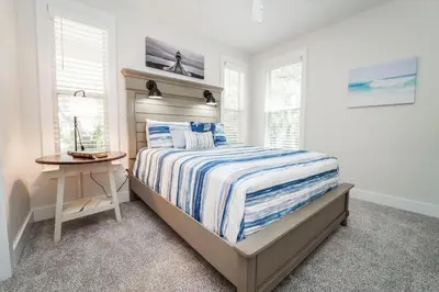a bedroom with a bed and a table and windows at 30A Beach House - Mar Chiquita in Watersound Beach