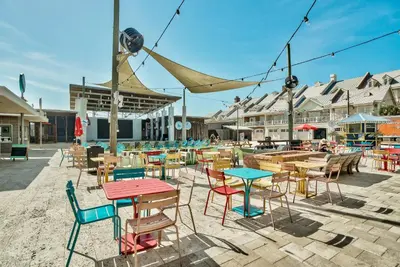 a group of tables and chairs in a patio at Prominence on 30A by Panhandle Getaways in Watersound Beach