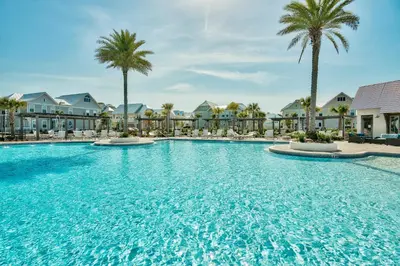 a large swimming pool with palm trees and buildings at Prominence on 30A by Panhandle Getaways in Watersound Beach