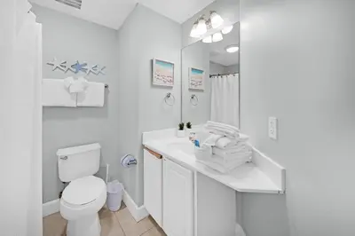 a white bathroom with a toilet and a sink at Sunrise Beach #2411 in Panama City Beach