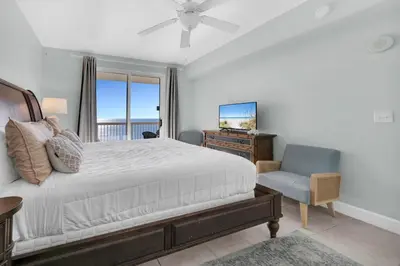 a bedroom with a bed and a chair and a television at Sunrise Beach #2411 in Panama City Beach