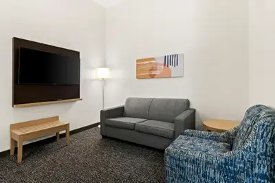 a living room with a couch and a chair and a tv at Spark by Hilton Panama City Beach in Panama City Beach