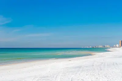 a beach with a group of people in the water at Holiday Inn Express & Suites Panama City Beach - Beachfront by IHG in Panama City Beach