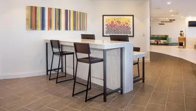 a bar in a lobby with chairs and a painting at Holiday Inn Express & Suites Panama City Beach - Beachfront by IHG in Panama City Beach