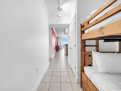 a bedroom with a bunk bed and a tiled hallway at Emerald Beach 2225 in Panama City Beach