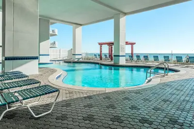 a swimming pool in a building with chairs and the ocean at Majestic Beach Towers 2-2003 in Panama City Beach