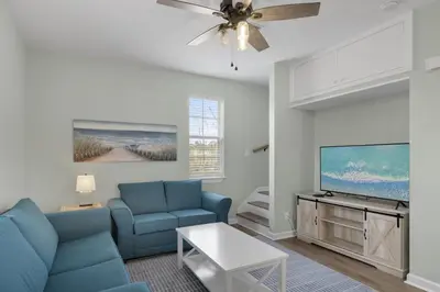 a living room with a blue couch and a tv at The Bungalows at Seagrove 114 in Seagrove Beach