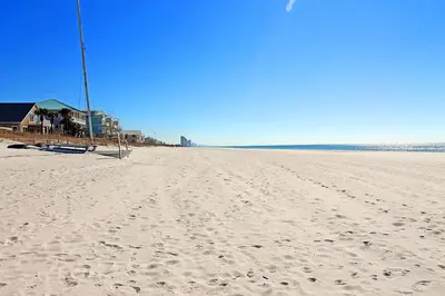 a beach with footprints in the sand and a house at Mariner West 205 in Panama City Beach