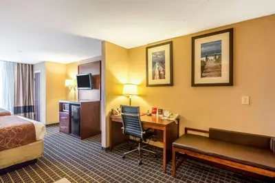 a hotel room with a bed and a desk and a bed and a room at Comfort Suites in Panama City Beach