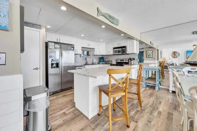 a kitchen with white cabinets and a table and chairs at Edgewater Tower 2-611 in Panama City Beach