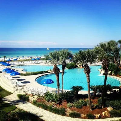 a large swimming pool with palm trees and the ocean at Edgewater Beautiful 2 bedroom 2 bath! in Panama City Beach