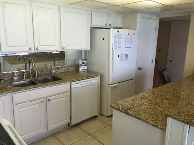 a kitchen with white cabinets and a white refrigerator at Edgewater Beautiful 2 bedroom 2 bath! in Panama City Beach