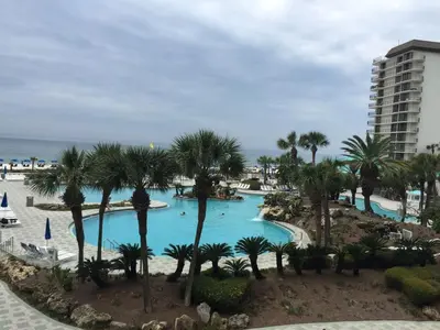 a view of a pool with palm trees and a building at Edgewater Beautiful 2 bedroom 2 bath! in Panama City Beach