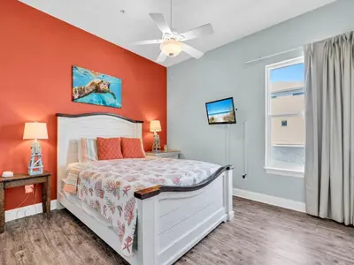 a bedroom with a bed with an orange wall at Vista del Mar I Rest-A-While 201 in Panama City Beach