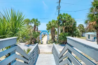 a boardwalk leading to a beach with palm trees at Vista del Mar I Rest-A-While 201 in Panama City Beach