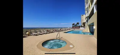 a swimming pool with chairs and the ocean in the background at Ocean Ritz - Family Tides - sleeps 12 in Panama City Beach