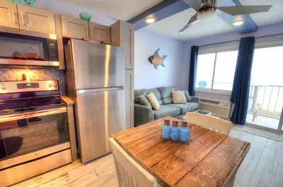 a kitchen with a refrigerator and a table and a couch at Emerald Villa in Panama City Beach