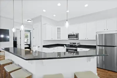 a kitchen with white cabinets and a black counter top at 30A Beach House - Caspian Sea-duction in Sunnyside