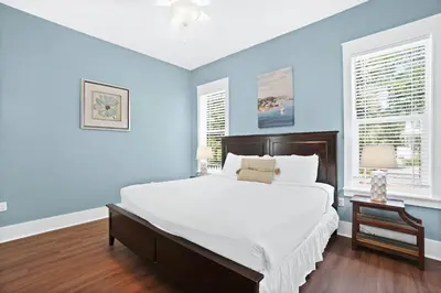 a blue bedroom with a large bed and two windows at 30A Beach House - Caspian Sea-duction in Sunnyside