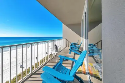 a balcony with two blue chairs and the ocean at Tidewater 314 NEW in Panama City Beach