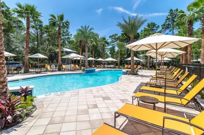 a swimming pool with yellow chairs and umbrellas at Magnolia Cottages by the Sea by Panhandle Getaways in Watersound Beach