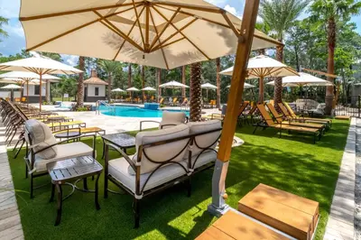 a group of tables and chairs with umbrellas next to a pool at Magnolia Cottages by the Sea by Panhandle Getaways in Watersound Beach